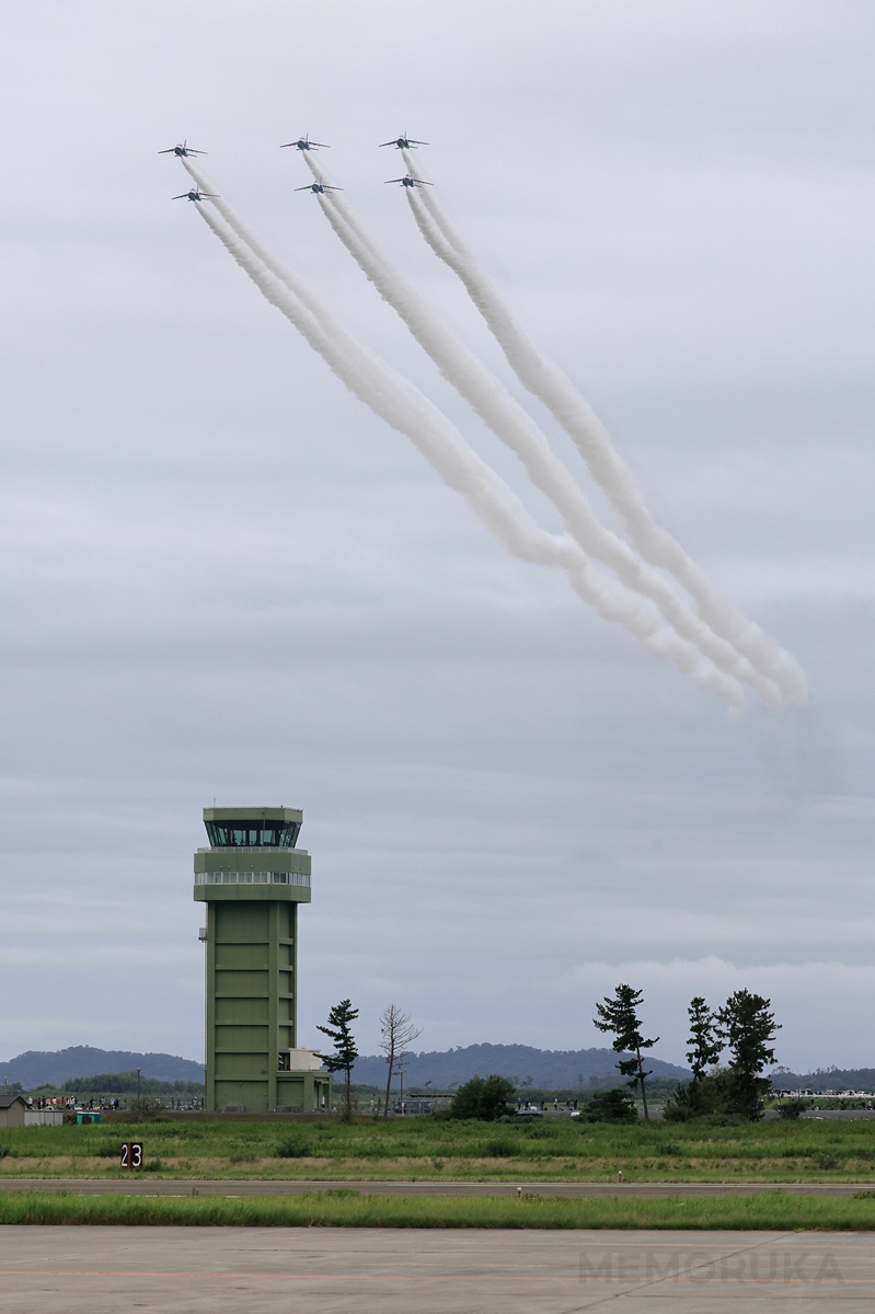 松島基地の管制塔上空を通過するブルーインバルスの写真